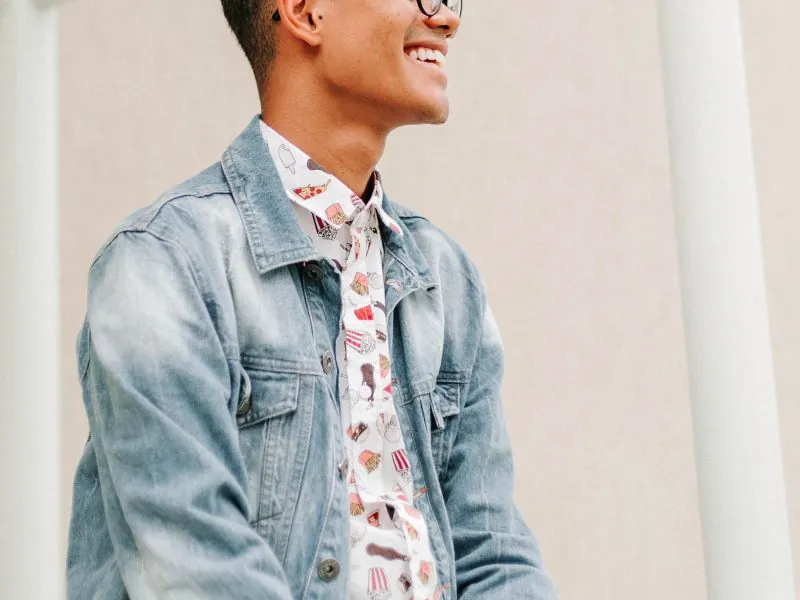 Jovem de jaqueta jeans sorrindo de perfil