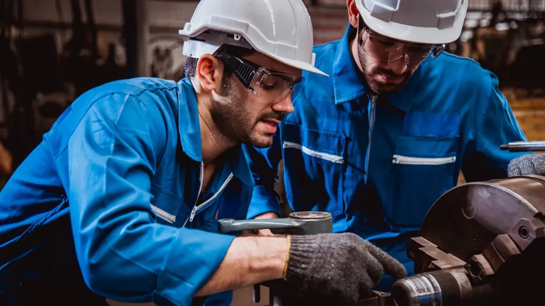 Dois técnicos de capacete conferindo informações em tablet na fábrica